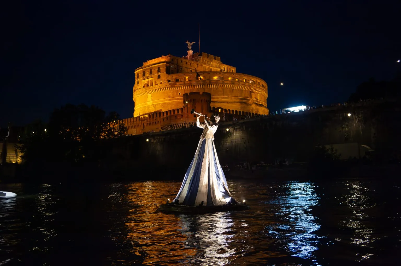 A flute player floats on the Tiber in front of the angel's palace in Rome during the show by the company ilotopia Drift.