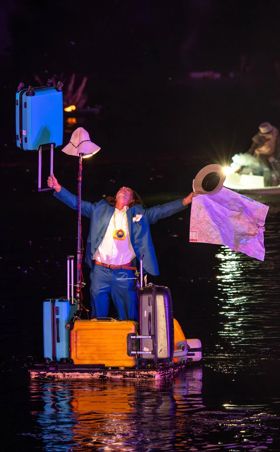A man on a wave of water made of luggage. A picture from the water show The Extraodinary Journey, ilotopie company