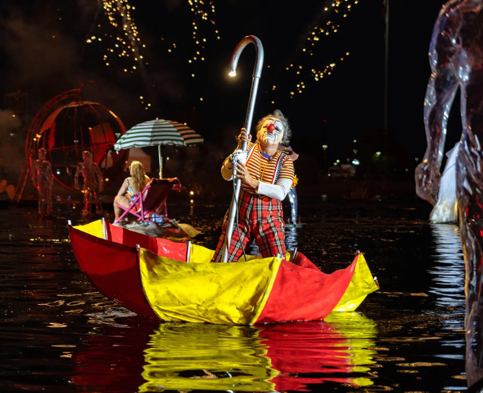 アクアティックパレード-A clown in an upside down umbrella floating on the water. An image of the show The Extraordinary Journey by ilotopie company