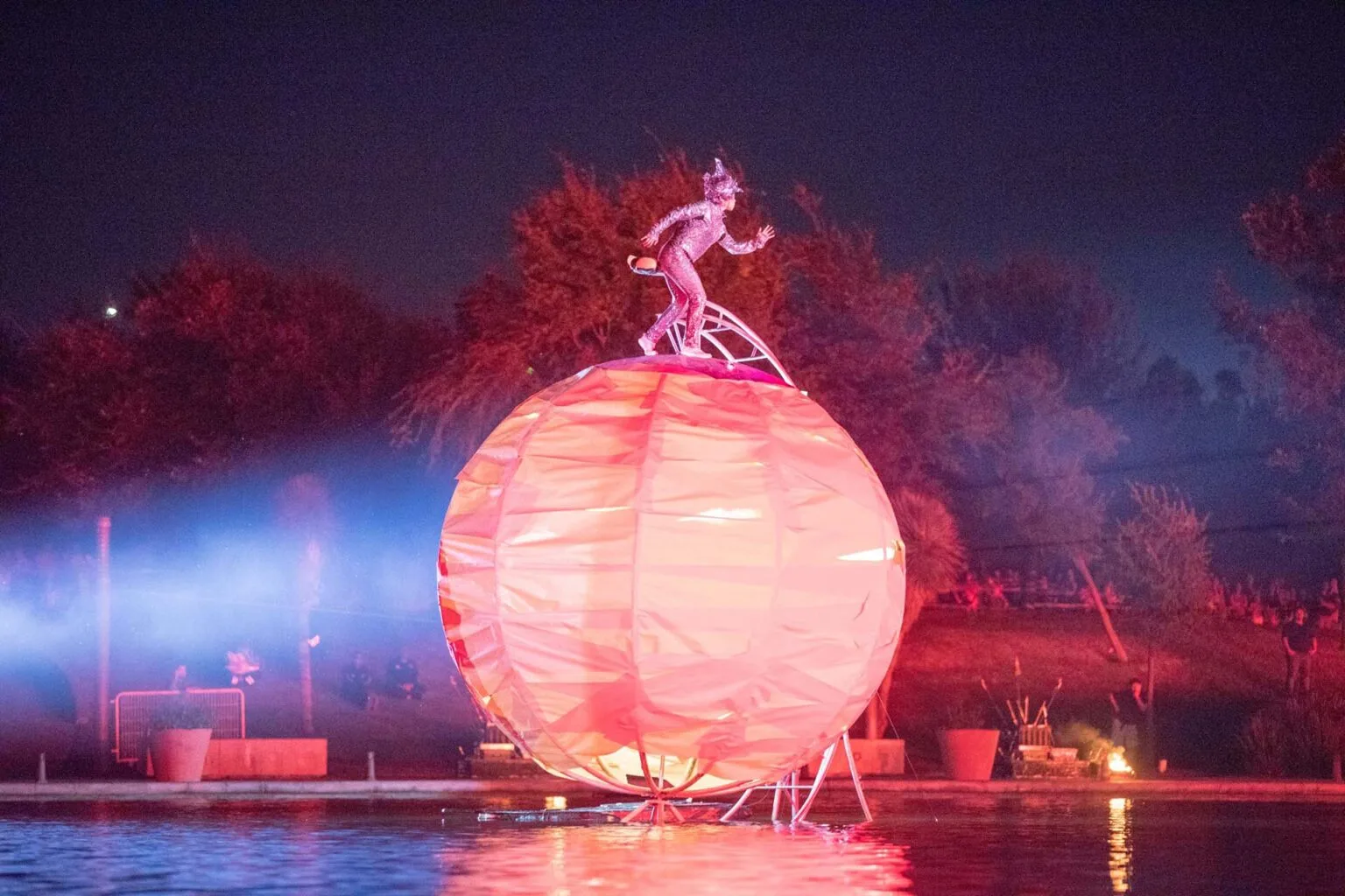 A big sphere on the water with a light character on it, a picture coming from the water show the Extraordinairy Journey by the ilotopie company