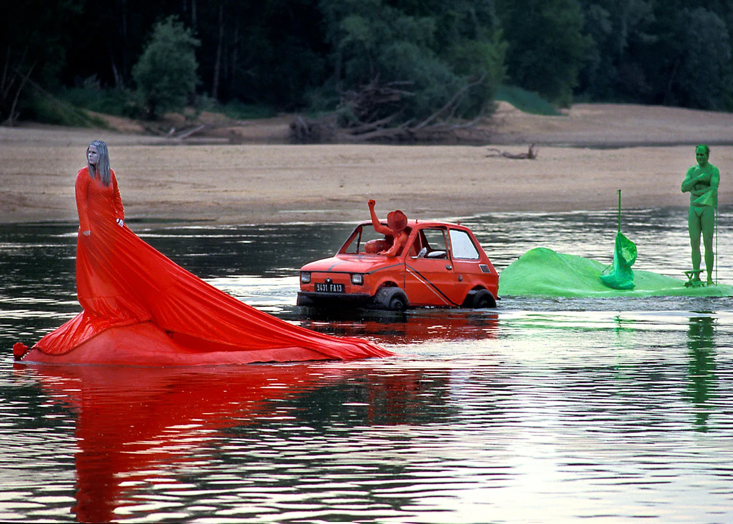 a red woman with a long red dress on a red island. On the back a red man in a red floating car.