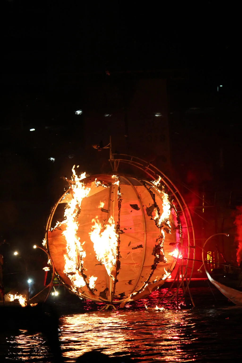 A giant ball on fire on the water at night. A part of the big water show The Extraodinary Journey by ilotopie