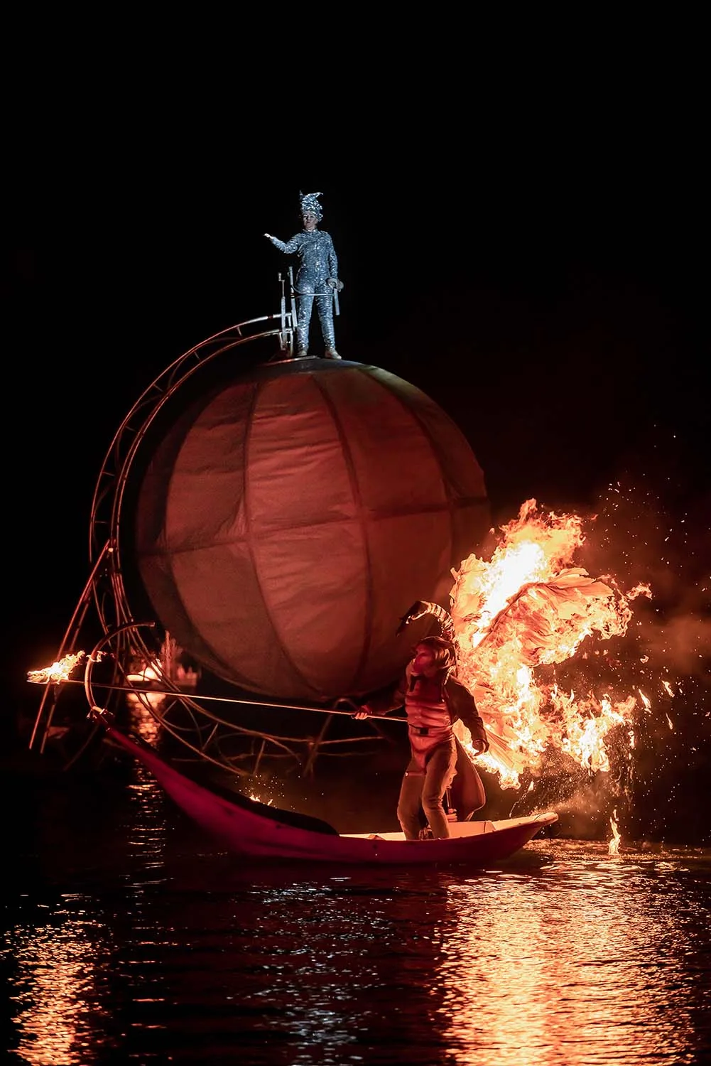 water show by the company ilotopie, the extraodinary Journey, here an angel on the water with its wings on fire and on the back a big sphere with a sinning character.
