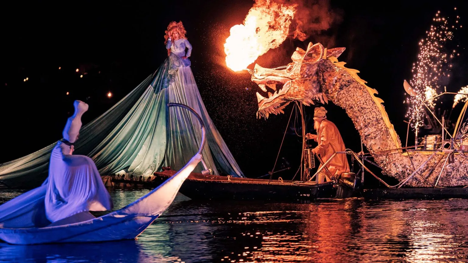 water show the Extraordinary Journey by ilotopie, here the water dragon breathe firing in front of a water diva and a strange white character, everybody on floating vehicules.