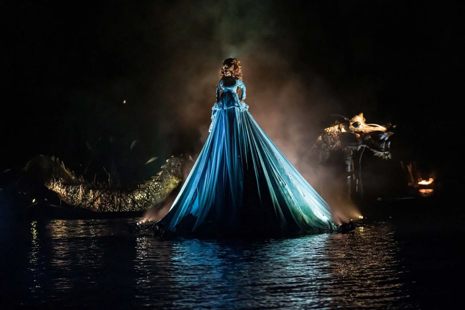 A queen on a giant dress floating on the water. A dragon sliding on her back. A picture from the water show The Extraodirary Journey by ilotopie the company.