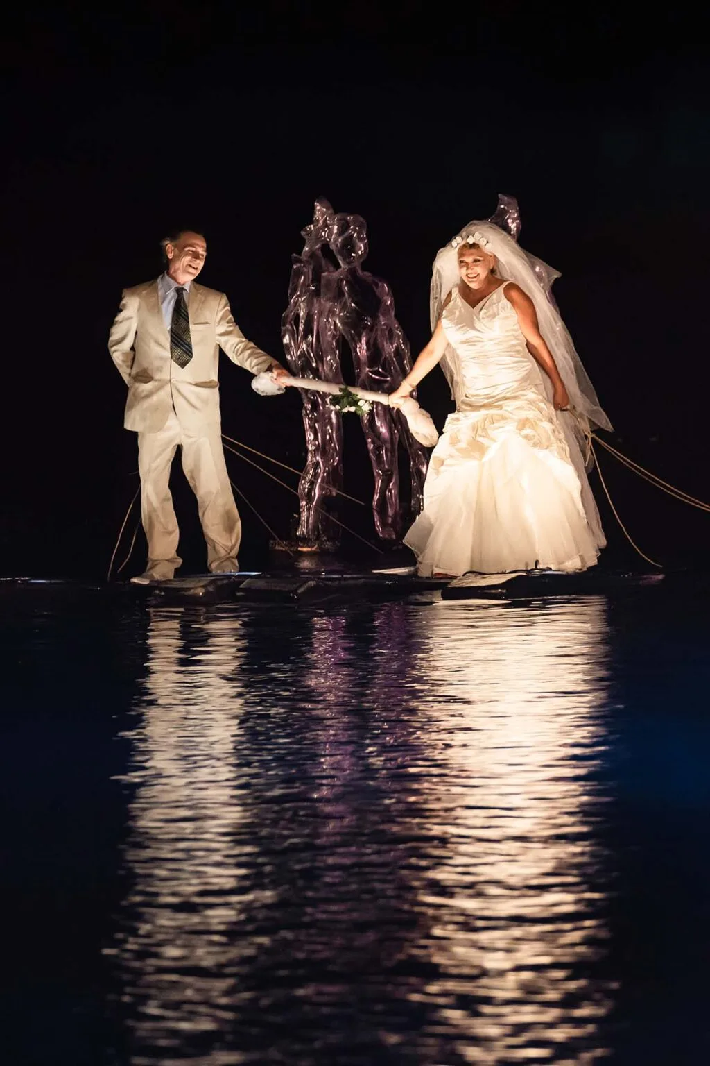 A weeding on the water. the married couple walking on the water, happy. Some ghosts on their back. a moment of the aquatic show the extraordinary Journey by ilotopie company.